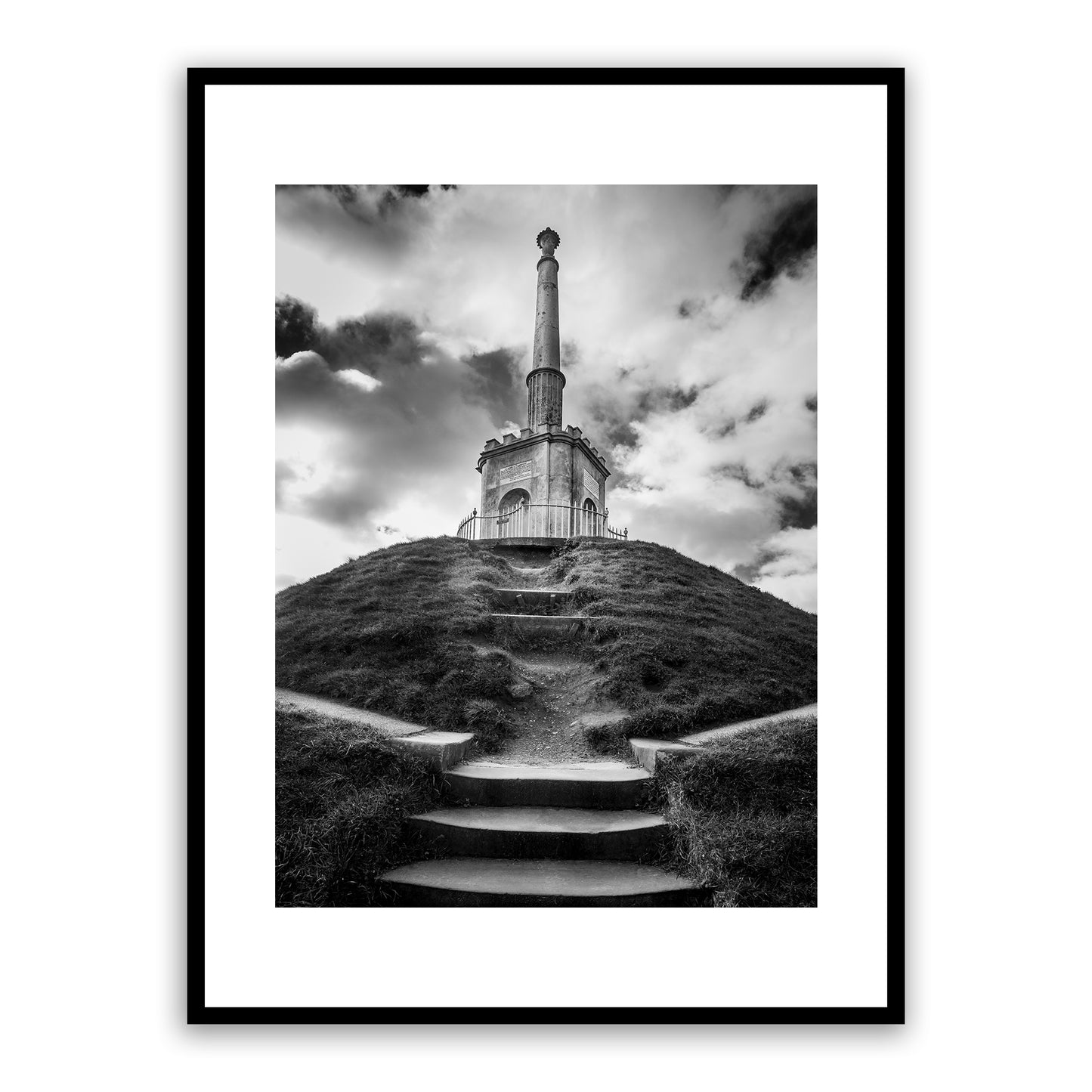 A centuries-old landmark, the iconic grade II listed Simmons Monument stands at the summit of Dane John Mound (which dates back to 1st century AD) in Dane John Gardens, Canterbury, Kent, England. Erected in 1803, the monument honours Alderman James Simmons, founder of the Kentish Gazette, who purchased and landscaped the gardens in 1790 as a gift to the city. Fine art black and white photography print for sale.