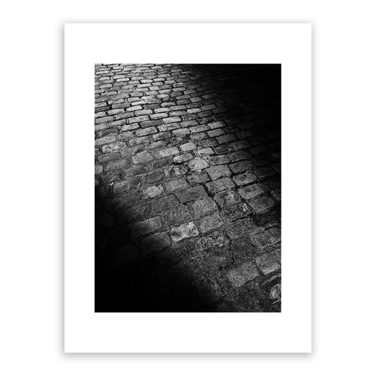 Sunlight shining through a doorway on to a Canterbury cobblestone street. Fine art black and white photograph for sale.