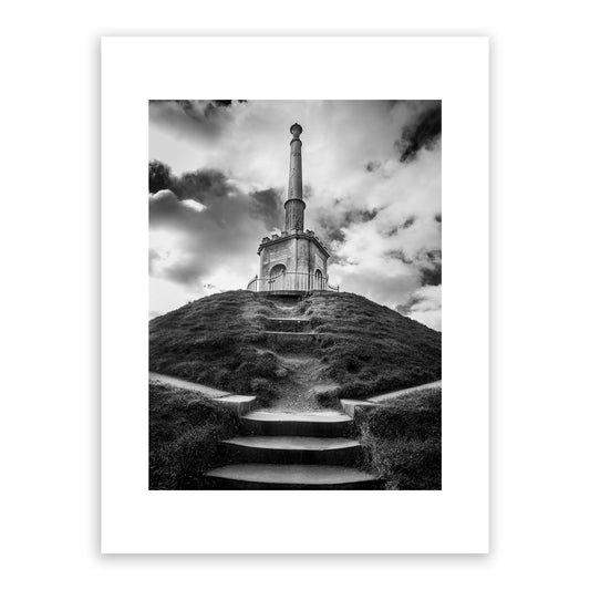 A centuries-old landmark, the iconic grade II listed Simmons Monument stands at the summit of Dane John Mound (which dates back to 1st century AD) in Dane John Gardens, Canterbury, Kent, England. Erected in 1803, the monument honours Alderman James Simmons, founder of the Kentish Gazette, who purchased and landscaped the gardens in 1790 as a gift to the city. Fine art black and white photography print for sale.