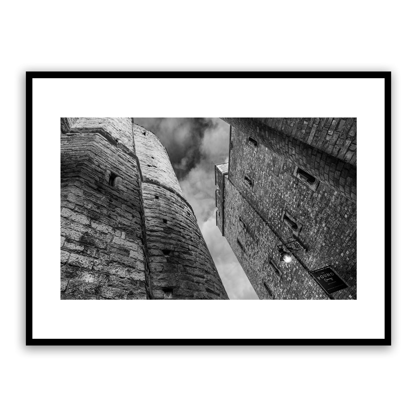 The Pound, One Pound Lane, Canterbury, Kent, England. Alleyway between one Pound Lane (former Victorian gaol now bustling bar and restaurant) and the medieval iconic Westgate Towers. Fine art black and white photography print for sale.